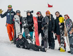 Grupa snowboardzistów uśmiecha się do zdjęcia na tle śniegu.