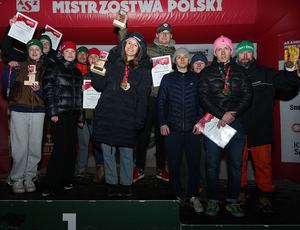 Grupa osób stojących na podium i dumnie prezentujących swoje nagrody.