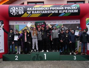 Grupa osób stojących na podium i dumnie prezentujących swoje nagrody.