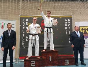 Zawodnicy karate w białych strojach stoją na podium