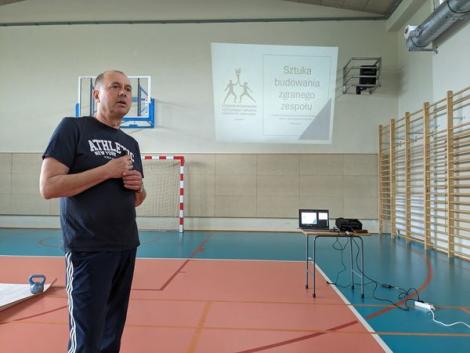 Zdjęcie nr 1 (6)
                                	                             hala sportowa, po lewej Paweł Ochwat, po prawej ekran ze slajdem wyświetlanym na rzutniku, widoczny tytuł slajdu: Sztuka budowania zgranego zespołu.
                            